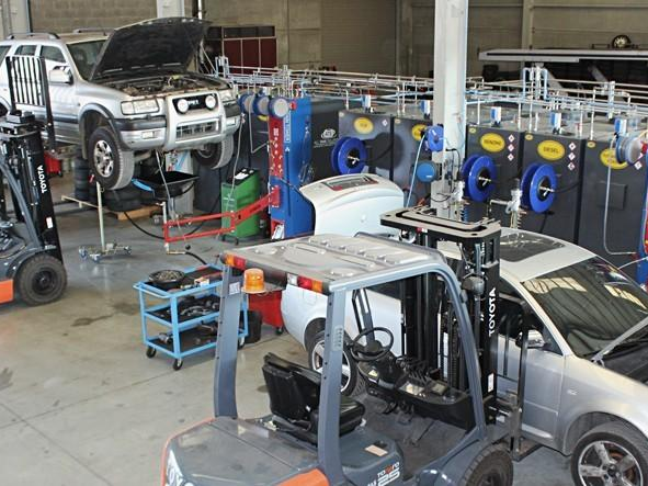 Vehicles raised on lifts and forklifts at work inside a dismantling workshop